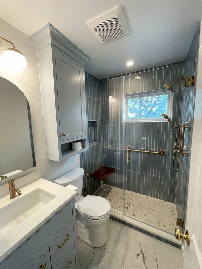 Blue Bathroom Ideas with vertical slate blue tile, brushed brass grab bar, and marble mosaic shower floor