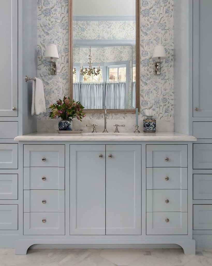 Blue and white bathroom with grey vanity, floral wallpaper, and gold mirror