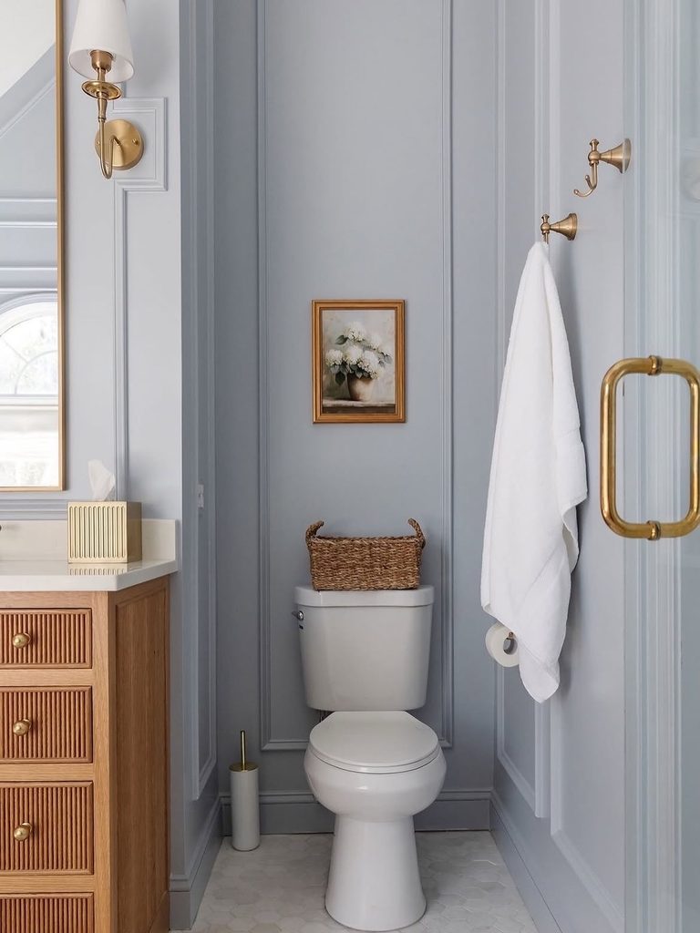 Blue bathroom with fluted oak vanity, brushed brass fixtures, and panelled walls