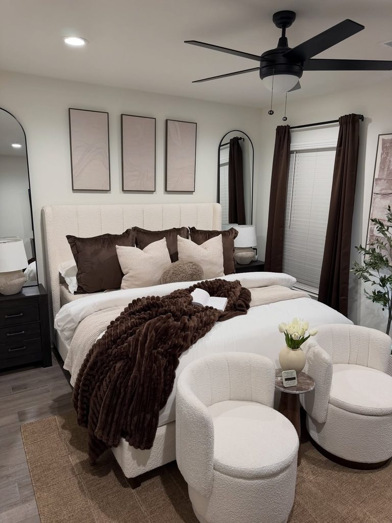 Cream boucle bedroom with dark brown curtains, faux fur throw, and arched mirror